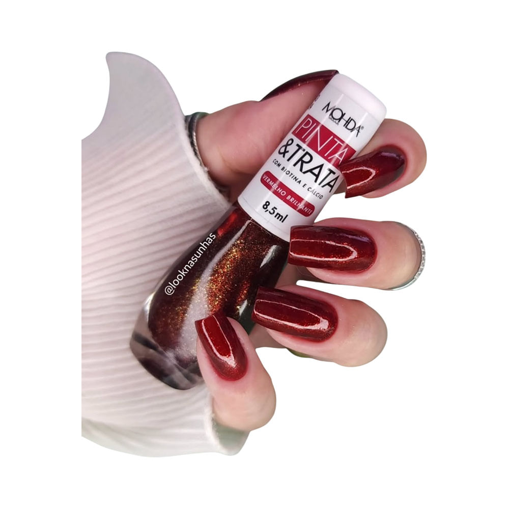 Mão segurando esmalte Mohda Pinta e Trata Vermelho Brilhante com unhas pintadas